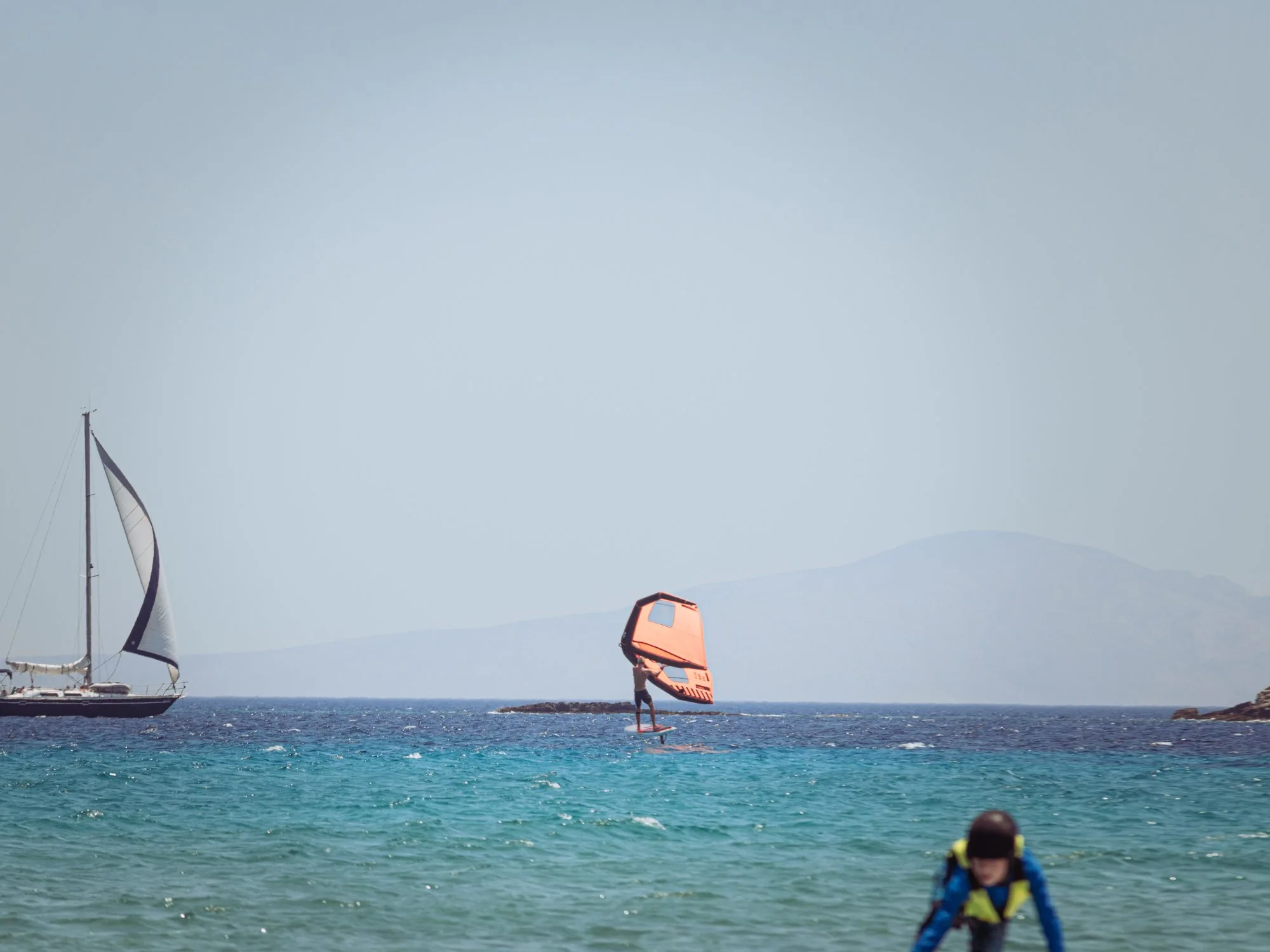 Wingfoiling Paros with sailboat
